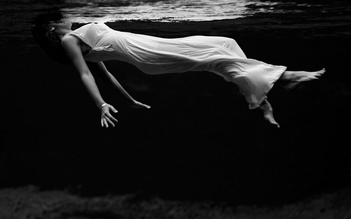 Woman in white dress floating underwater