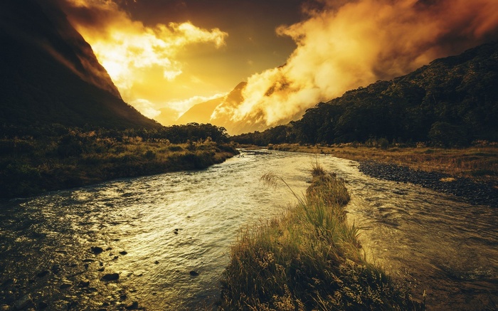 River flowing through a valley at sunset with clouds