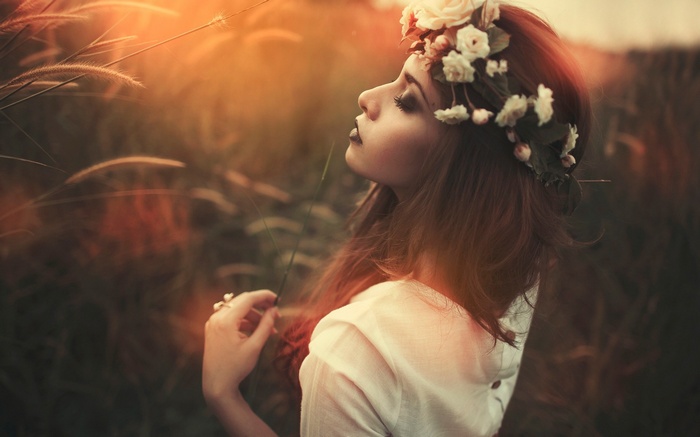 Woman with flower crown in field at sunset