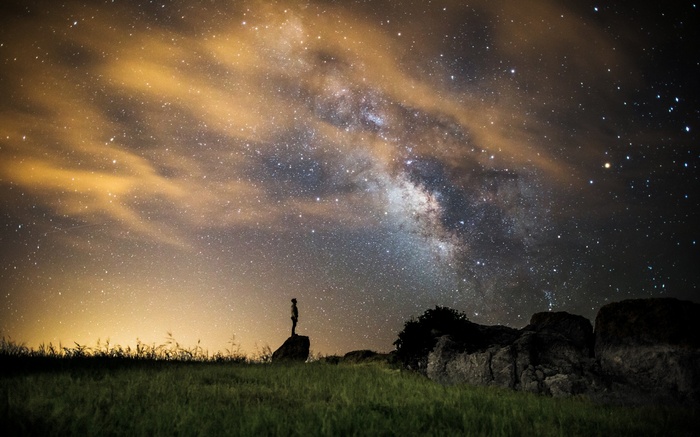 Person standing under the Milky Way galaxy