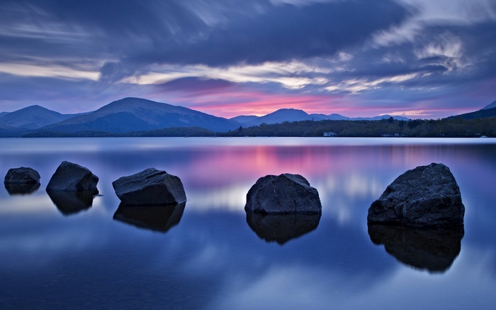 Mountains and stones reflected in a lake at sunset