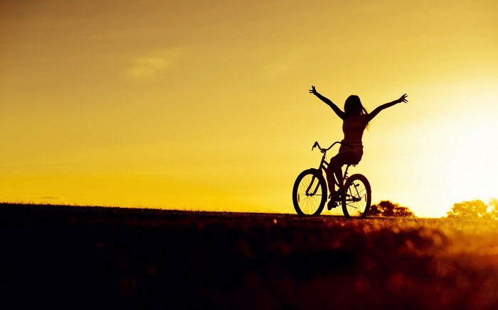 Silhouette of a woman on a bicycle at sunset