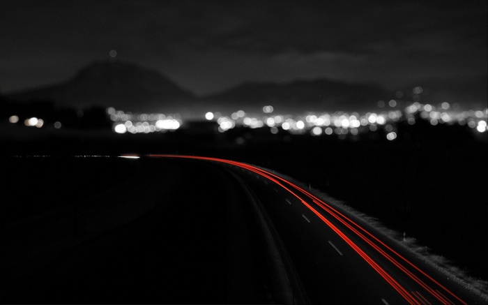 Night road with red light trails and city lights