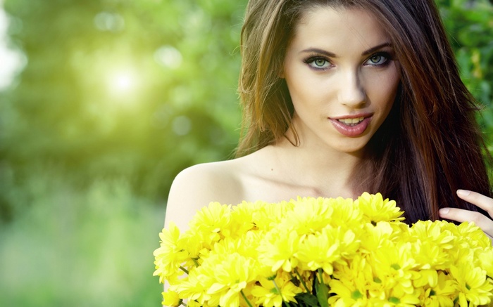 Woman with green eyes holding yellow flowers outdoors