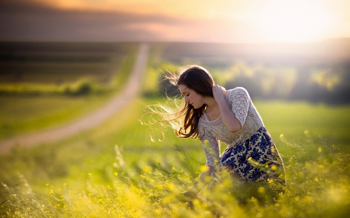Woman in a field of yellow flowers at sunset