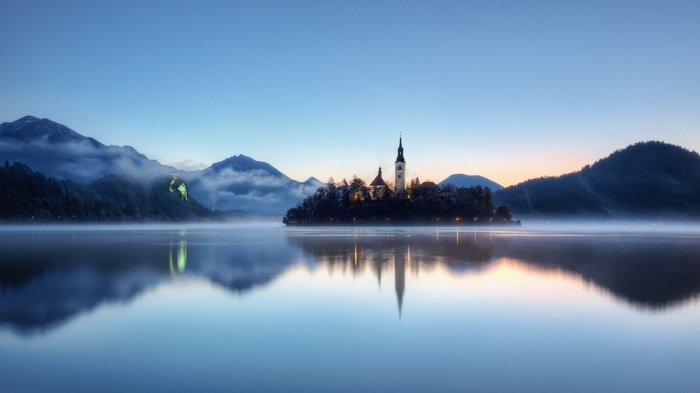 Island church with mountains and lake reflection