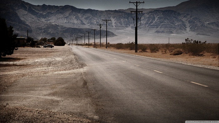 Desert road with mountains and power lines