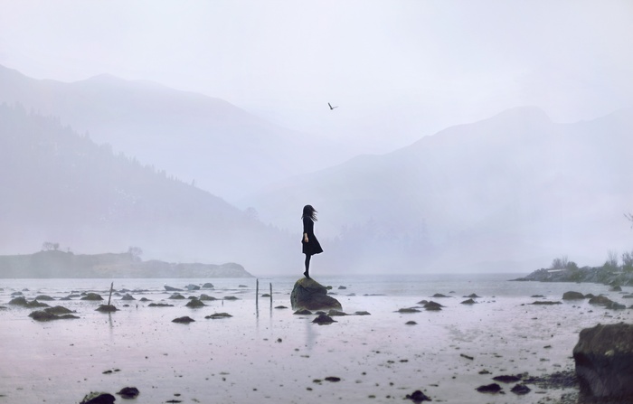 Woman standing on a rock in a misty landscape