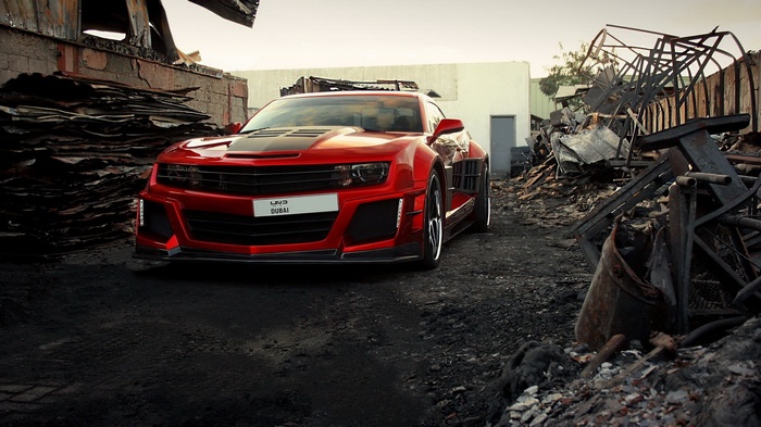 Red Chevrolet Camaro in a junkyard