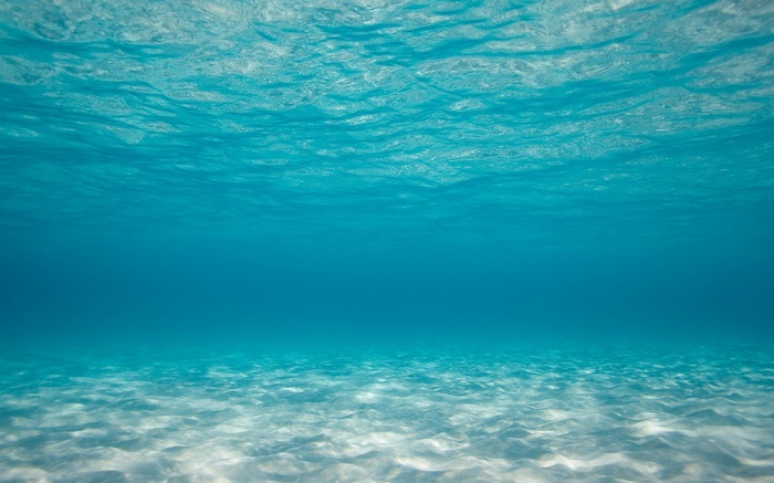 Underwater view of a sandy seabed with light filtering through the water
