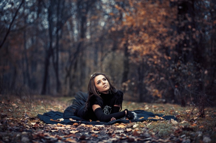 Woman in black dress lying on blanket in autumn forest