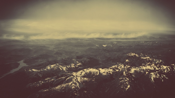 Sepia toned aerial view of snow-capped mountains and a river
