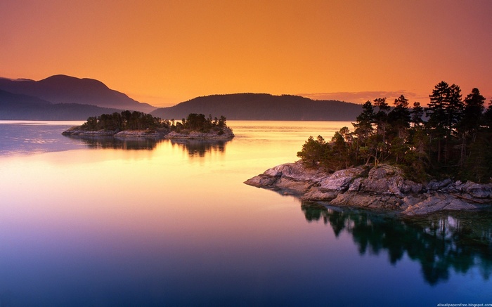 Sunset over a calm lake with islands and mountains