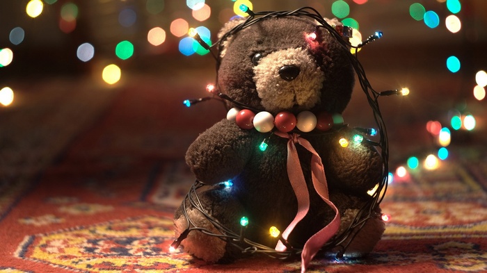 Teddy bear wrapped in colorful Christmas lights