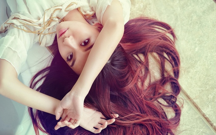 Asian woman with long red hair lying down