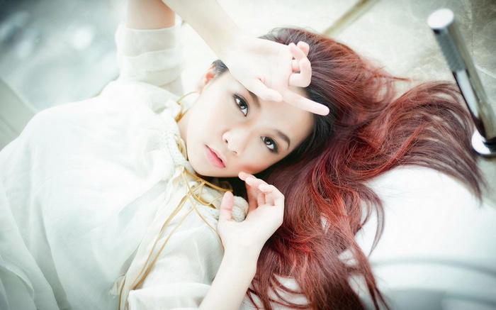Asian woman with red hair lying down