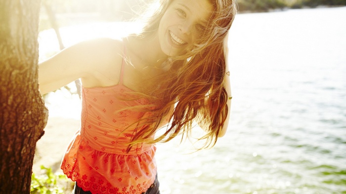 Woman smiling by the water in sunlight