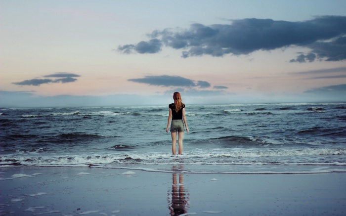 Woman standing in the ocean at sunset