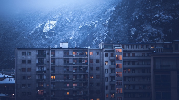 Apartment buildings against a snowy mountain at dusk