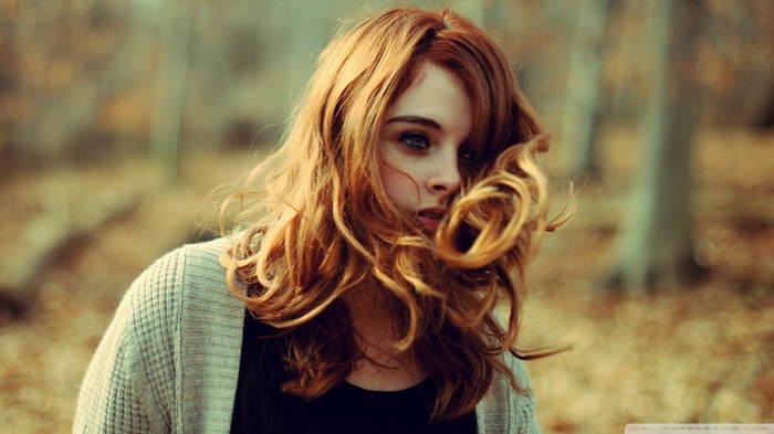 Redhead woman with windblown hair in a forest