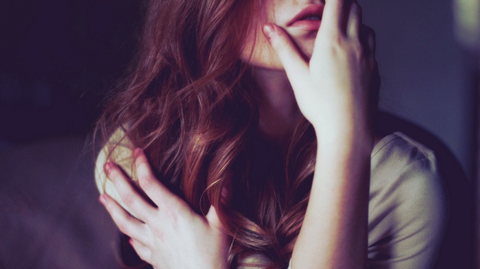 Woman with long auburn hair covering her face