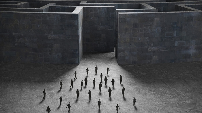 People entering a dark stone labyrinth