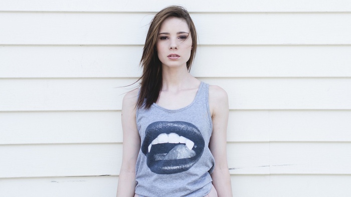 Woman in tank top with lips graphic standing against wall