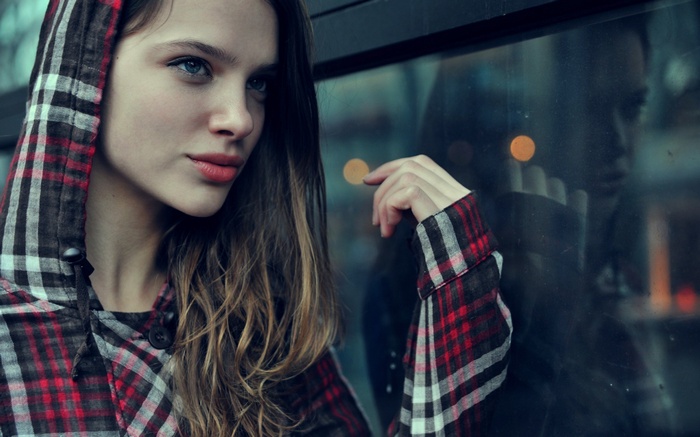 Woman with blue eyes wearing a plaid hooded jacket