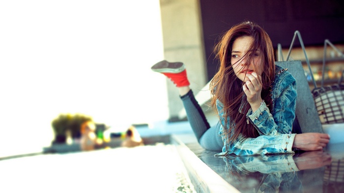 Woman in jean jacket with red Converse shoes