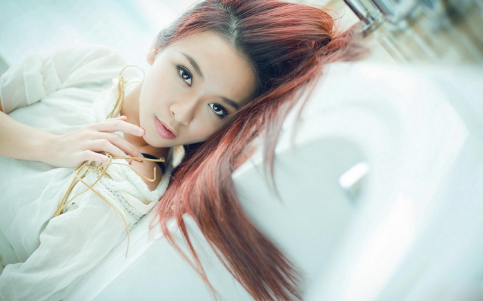 Asian woman with red hair lying down