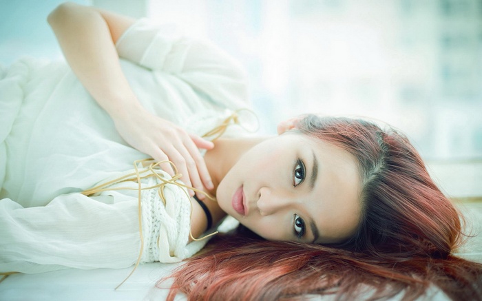Asian woman with dyed red hair lying down