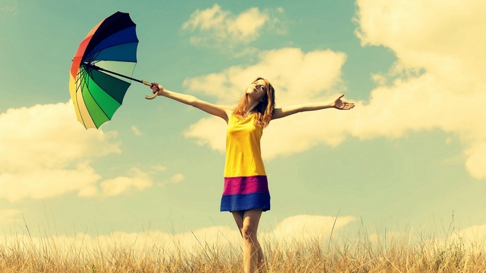 Woman holding a colorful umbrella in a field