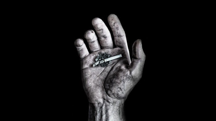A hand holding a cigarette butt and ash