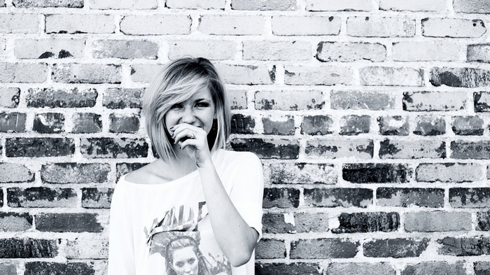 Ellie Goulding smiling in front of a brick wall