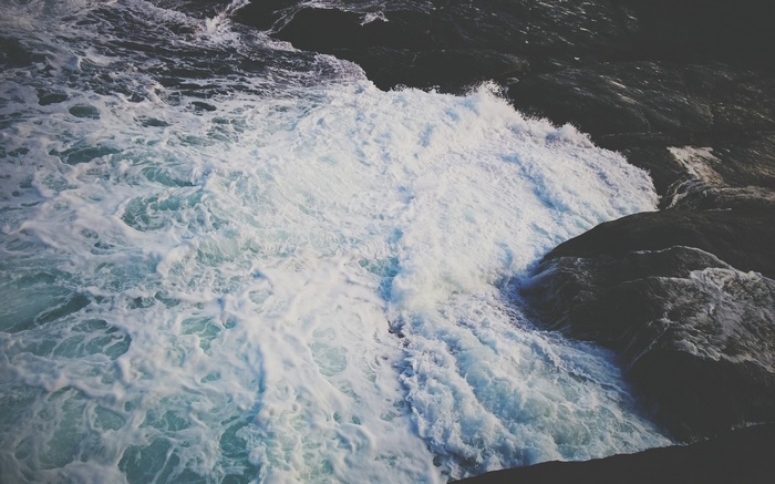 Waves crashing against dark rocks on the coast