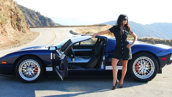 Denise Milani poses with a blue Ford GT on a mountain road