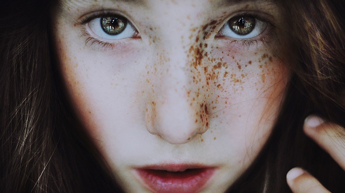 Close-up portrait of a young girl with freckles