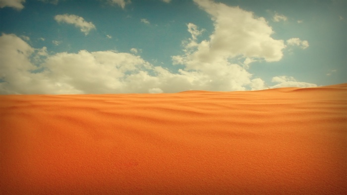 Desert sand dunes under a cloudy sky