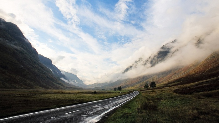 A scenic road winds through a misty mountain valley