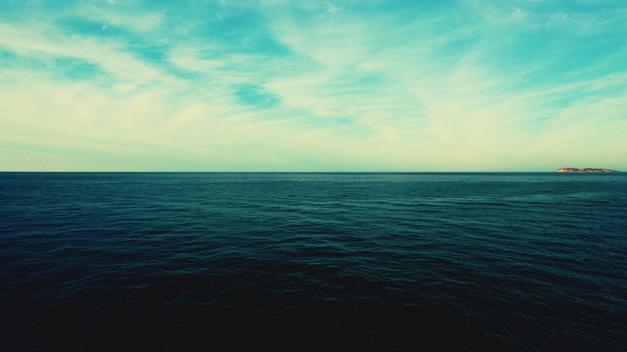 Ocean horizon with clouds and a distant island