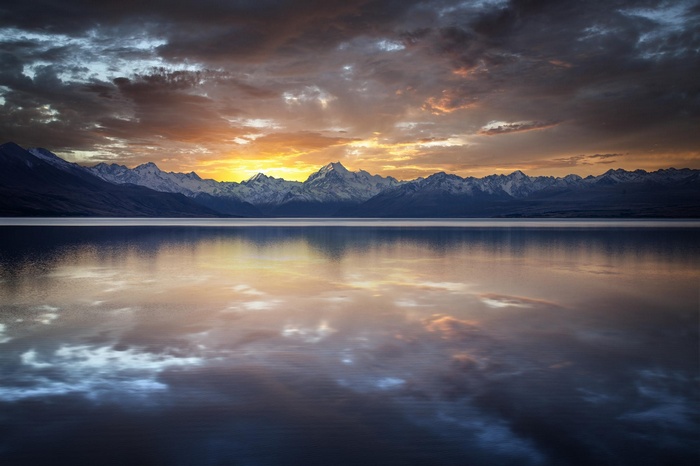 Sunset over snow-capped mountains reflected in a lake