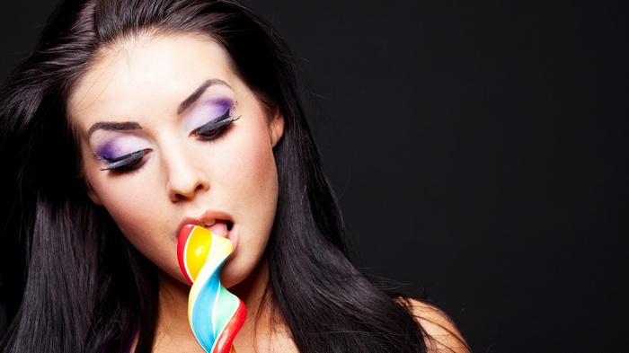 Woman with colorful lollipop and dramatic makeup