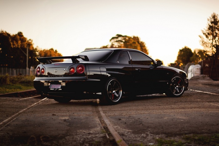 Black Nissan Skyline R34 GT-R parked on train tracks