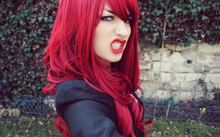 Woman with red hair and pierced lips outdoors