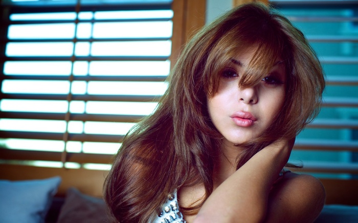 Woman with long brown hair in front of blinds