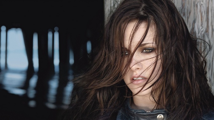 Kristen Stewart posing against a wooden post