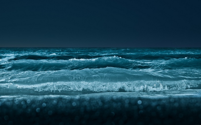 Dark blue sea with crashing waves and bokeh