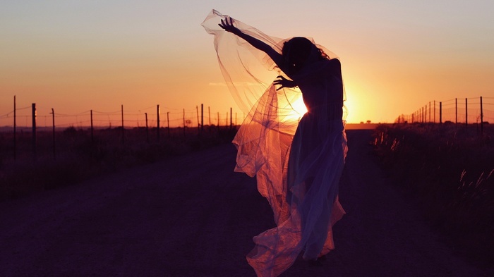 Woman in a dress dancing at sunset