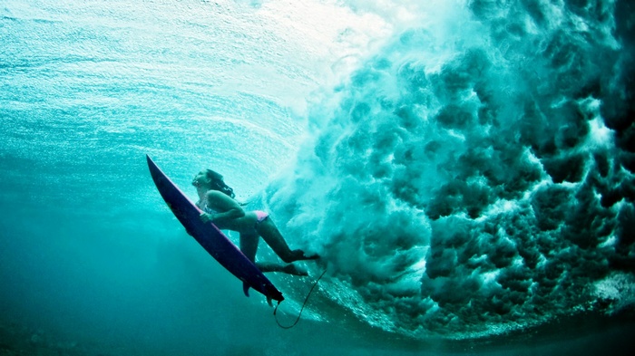 Woman surfing underwater with a surfboard