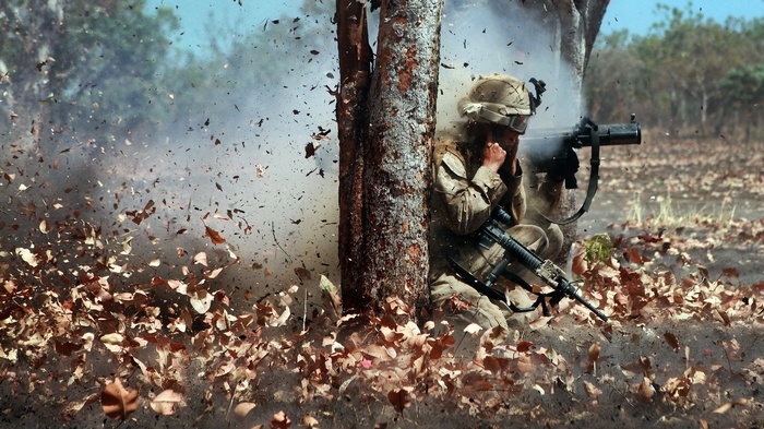 US Marine firing a weapon during an explosion